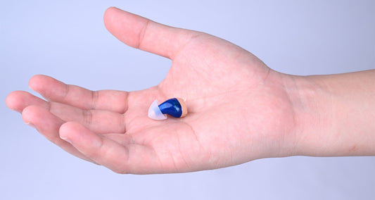 There is a small hearing aid in the palm of the hand.
