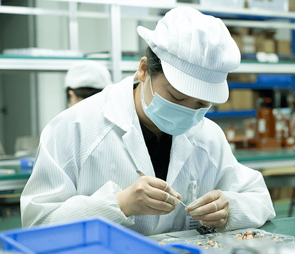 Person in a white lab coat and mask working in a laboratory setting.